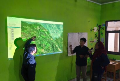 Community members study a projected forest map during an FPIC consultation in Enrekang